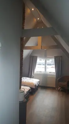 a attic room with two beds and a window at Het Zwanennest in Den Ilp