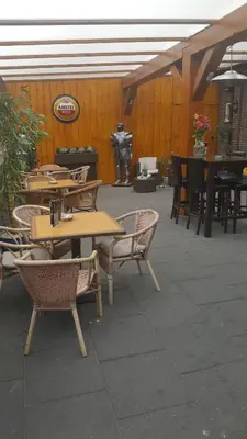 a patio with tables and chairs and a man standing in the background at Het Zwanennest in Den Ilp