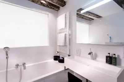 a white bathroom with a tub and a sink at 18th Century Groundfloor Canal House with patio/garden in Amsterdam