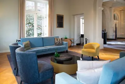 a living room with a blue couch and chairs at Pestana Amsterdam Riverside in Amsterdam