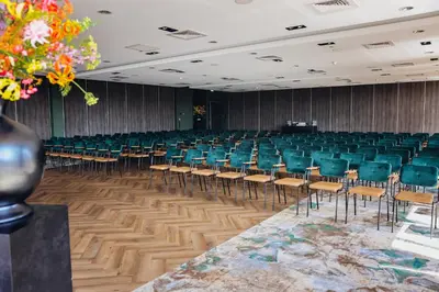 an empty lecture hall with green chairs and a podium at Van Der Valk Hotel Almere in Almere