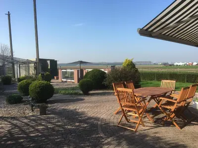 a wooden table and chairs on a patio at B&B De Kaagse Koe in Huigsloot