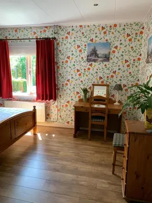 a bedroom with floral wallpaper and a desk at B&B De Kaagse Koe in Huigsloot