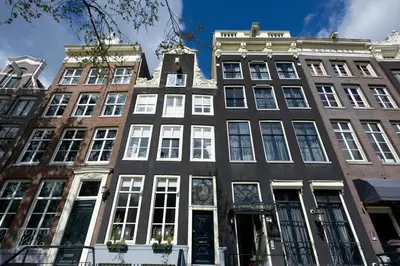 a tall building with white windows on a city street at Canal House in Amsterdam