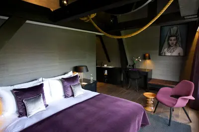 a bedroom with a large bed and a pink chair at Canal House in Amsterdam
