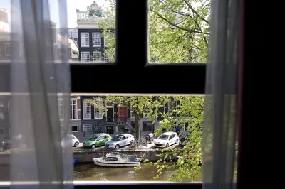 a view from a window of a canal with cars at Canal House in Amsterdam