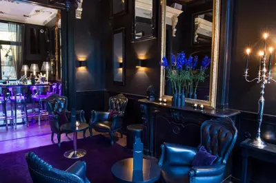 a bar with blue chairs and tables and a mirror at Canal House in Amsterdam