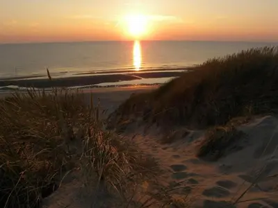 a sunset on a beach with the ocean and the sand at Holiday Home in Beemster by Windmill in Middenbeemster