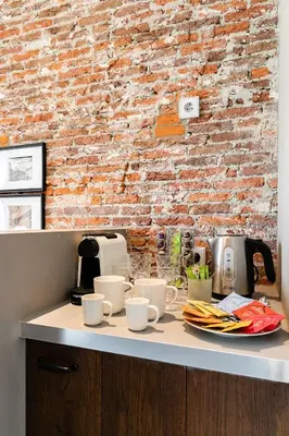 a counter with cups and plates and a brick wall at Boutique Hotel 't Vosje in Haarlem