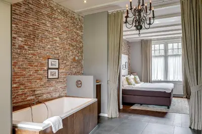 a bathroom with a brick wall and a tub and a bed at Boutique Hotel 't Vosje in Haarlem