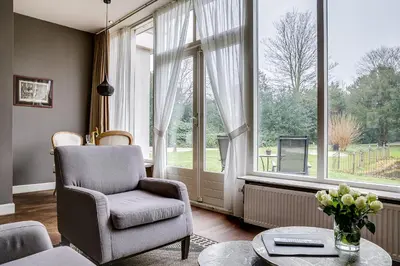 a living room with a chair and a large window at Boutique Hotel 't Vosje in Haarlem