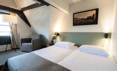 a hotel room with two beds and a chair at Hapimag Apartments Amsterdam in Amsterdam