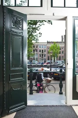 an open door to a building with a woman standing outside at Hapimag Apartments Amsterdam in Amsterdam