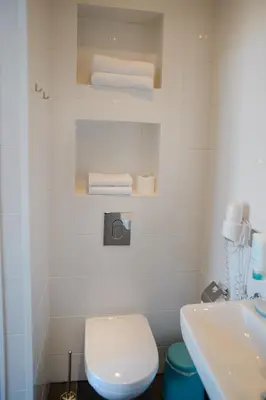 a bathroom with a toilet and a sink and towels at Hotel Grand Cafe Deight in Zandvoort
