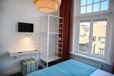 a bedroom with a bed and a desk and a window at Hotel Grand Cafe Deight in Zandvoort
