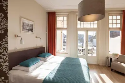 a bedroom with a large bed with blue pillows at Hotel Grand Cafe Deight in Zandvoort
