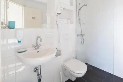 a white bathroom with a sink and a toilet at Hotel Grand Cafe Deight in Zandvoort