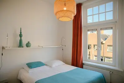 a bedroom with a bed next to a window at Hotel Grand Cafe Deight in Zandvoort