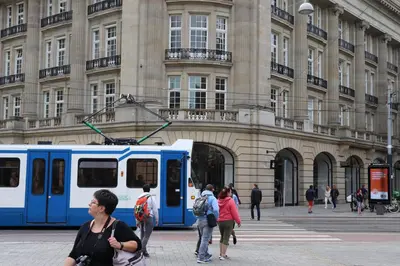 a blue and white train in front of a building at Amsterdam Hostel Leidseplein in Amsterdam