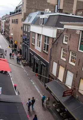 a group of people walking down a street with buildings at Amsterdam Hostel Leidseplein in Amsterdam