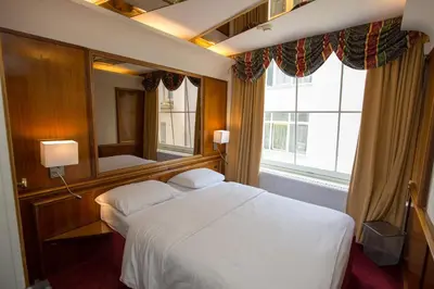 a bedroom with a white bed and a large window at Rembrandtplein Hotel in Amsterdam