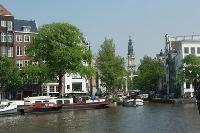 a group of boats docked on a river with buildings at Rembrandtplein Hotel in Amsterdam