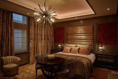 a bedroom with a bed and a table and a chandelier at Hotel TwentySeven - Small Luxury Hotels of the World in Amsterdam