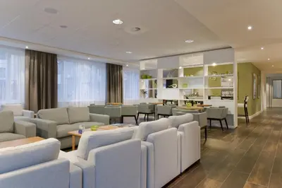 a waiting room with couches and tables and chairs at Holiday Inn Express Amsterdam - Schiphol by IHG in Hoofddorp