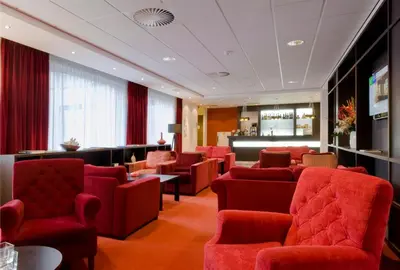 a waiting room with red chairs and a bar at Holiday Inn Express Amsterdam - Schiphol by IHG in Hoofddorp