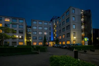 two tall buildings in a parking lot at night at Holiday Inn Express Amsterdam - Schiphol by IHG in Hoofddorp