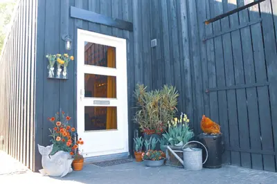 a blue house with a white door and some plants and flowers at Tulpenhuys in Hoogmaden