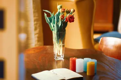 a vase of flowers and candles on a table at Tulpenhuys in Hoogmaden