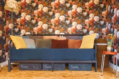 a blue couch in a room with a floral wallpaper at Tulpenhuys in Hoogmaden
