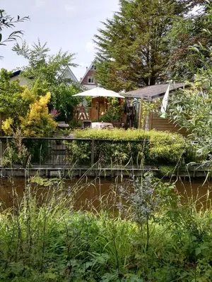 a house with a table and umbrella next to a river at De Zes Wielen in Alkmaar