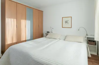 a bedroom with a white bed and a wooden cabinet at Huize Mare Appartementen in Bergen aan Zee