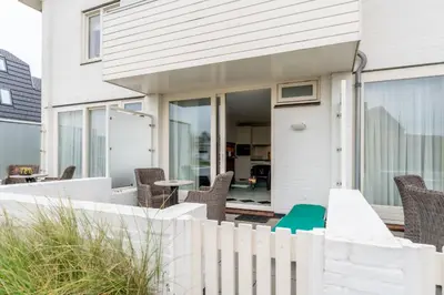 a white fence in front of a house at Huize Mare Appartementen in Bergen aan Zee