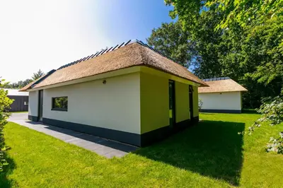 a small yellow and white building in a yard at Dutchen Suitelodges Gooilanden in Loosdrecht