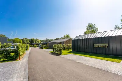 a road leading to a black building with trees at Dutchen Suitelodges Gooilanden in Loosdrecht