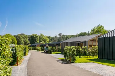 a man standing in a garden next to a building at Dutchen Suitelodges Gooilanden in Loosdrecht