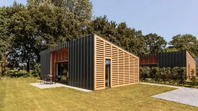 a small black and wooden house in a yard at Dutchen Suitelodges Gooilanden in Loosdrecht