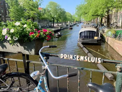 a bike parked on a railing next to a canal at Jordan Canal Studio in Amsterdam