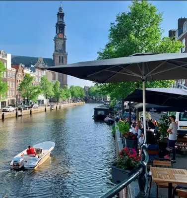 a boat on a river with a clock tower at Jordan Canal Studio in Amsterdam