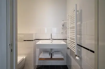 a white bathroom with a sink and a tub at Numa Amsterdam Oosterpark in Amsterdam