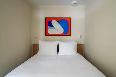 a bedroom with a bed with white sheets and a painting at Numa Amsterdam Oosterpark in Amsterdam