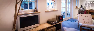 a living room with a flat screen tv and a chair at Joans B&B in Zaandam