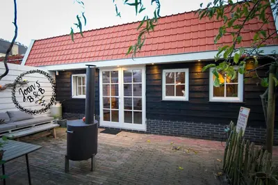 a house with a red roof and a bench in front of it at Joans B&B in Zaandam