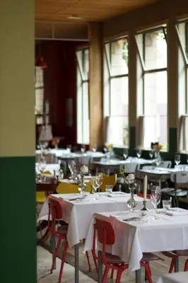 a dining room with white tables and chairs and windows at Cafe Modern in Amsterdam
