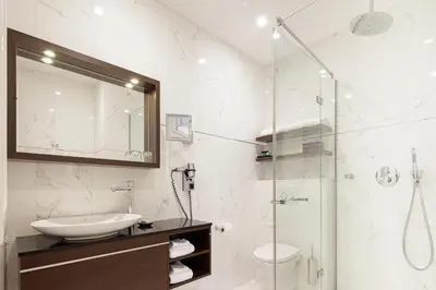 a bathroom with a sink and a glass shower at Boutique Hotel Notting Hill in Amsterdam