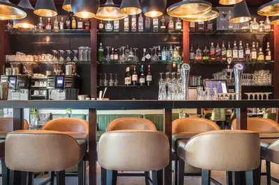 a bar with brown chairs and a counter with bottles at Boutique Hotel Notting Hill in Amsterdam