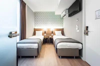 a hotel room with three beds and a table at Melrose Hotel in Amsterdam